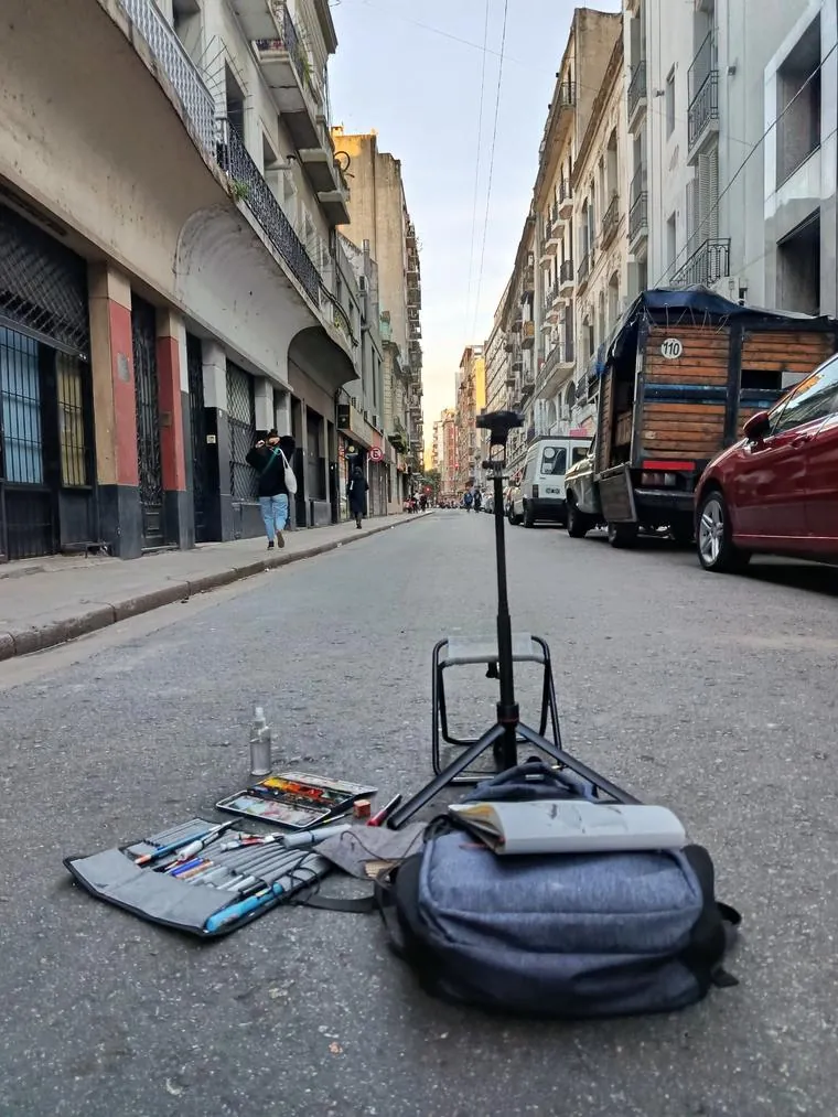 Banquito plegable, trípode, mochila, acuarelas y un sketchbook en medio de una calle del centro